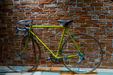 Kırmızı tuğla duvarın yanında şehir sarı bisikleti 