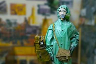 Fabrikanın önünde duran gaz maskeli ve radyasyon önlüklü adam. Arkaplan bulanık