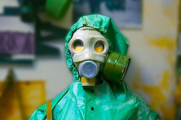 Man wearing gas mask  and radiation protection suit standing infront of factory. Background out of focus