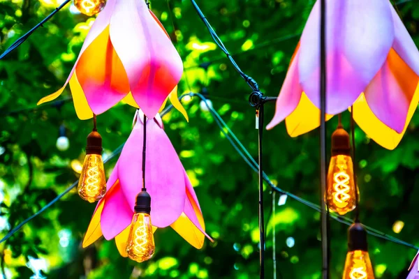 Närbild Garland Med Glödlampor Och Konstgjorda Blommor Trädgården — Stockfoto