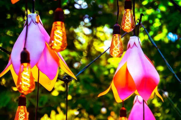 Närbild Garland Med Glödlampor Och Konstgjorda Blommor Trädgården — Stockfoto