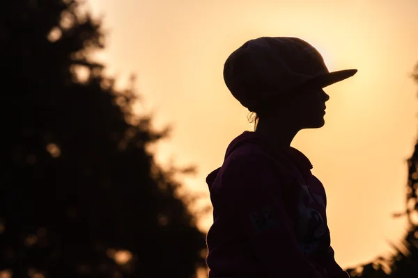 Giovanissima ragazza seduto silhouetted — Foto Stock