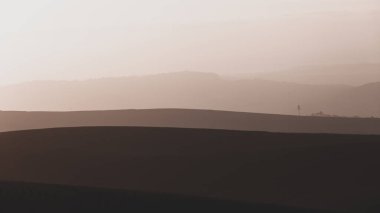 Kırsal tarım arazileri tepeleri manzaralı şafak vakti açık gökyüzü sepya renkleriyle panoramik ufuk manzarası üzerinde çelişiyor