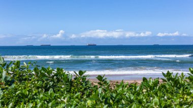 Liman girişini bekleyen mavi okyanus ufkuna demir atmış deniz gemileriyle sahil şeridi..