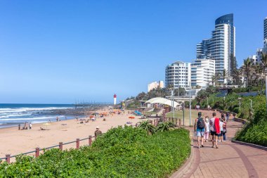 Public walking pathway along beach ocean sea landscape with apartment buildings and hotels along the green vegetation landscape.