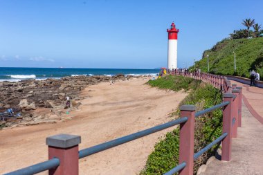 Kırmızı beyaz deniz fenerine yakın bina. Mavi gökyüzüne karşı okyanus tekneleri için uyarı güvenliği için..