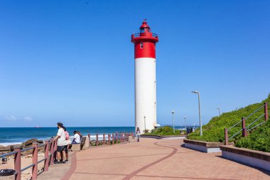 Kırmızı beyaz deniz fenerine yakın bina. Mavi gökyüzüne karşı okyanus tekneleri için uyarı güvenliği için..