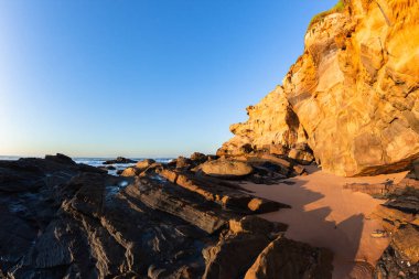 Plaj kumtaşı uçurumu detayları şekillendirir kayalık kıyı şeridi sabah manzarası.