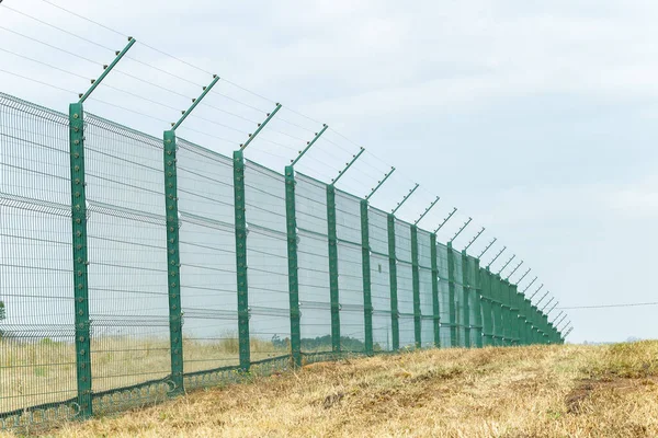 New constructed security steel fencing with electrified wires along property boundary outdoors summers day.