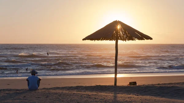 Beach Ocean Shoreline Man Sitting Silhouetted Next Wood Umbrella Watching — Stock Photo, Image