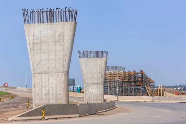 Industrial construction new road highway overpass junction expansion flyover concrete pillars columns concrete steel structures halfway progress of  building project in countryside.