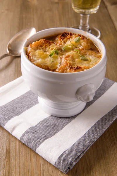 Sopa de cebola francesa em uma mesa de madeira com um copo de vinho branco — Fotografia de Stock