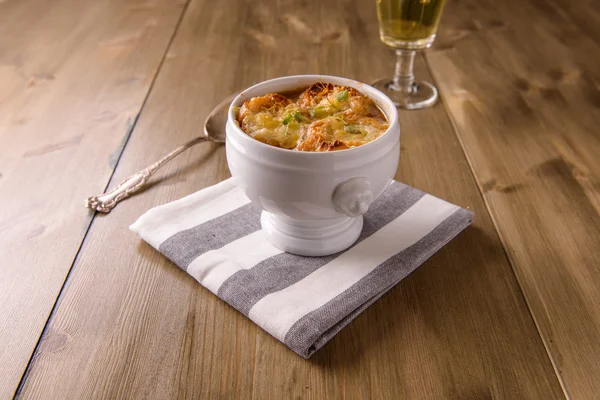 Franse uiensoep op een houten tafel met een glas witte wijn — Stockfoto