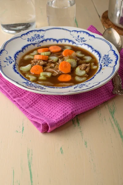 Chicken soup on old vintage table with carrots and selery on top