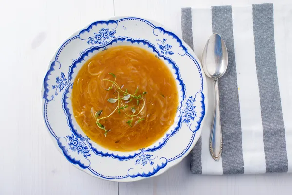 Klassische französische Zwiebelsuppe auf einem weißen Holztisch mit etwas rotem — Stockfoto