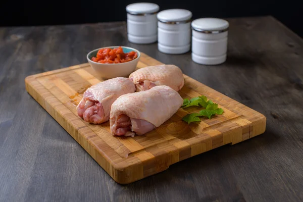 Rohes Huhn auf einem Schneidebrett mit etwas Salsa und Gemüse — Stockfoto