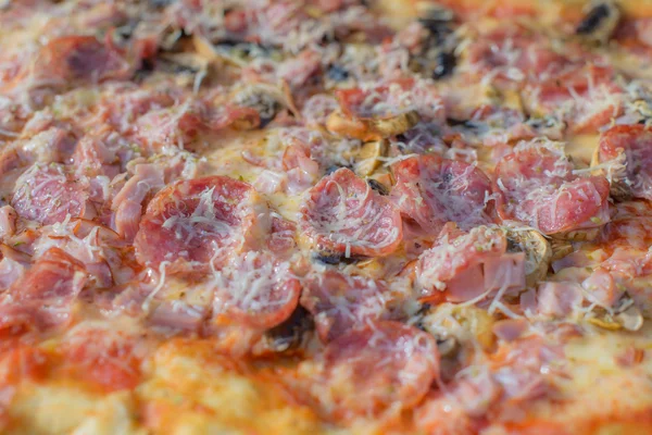 Primo piano di pizza condita con formaggio e salame — Foto Stock