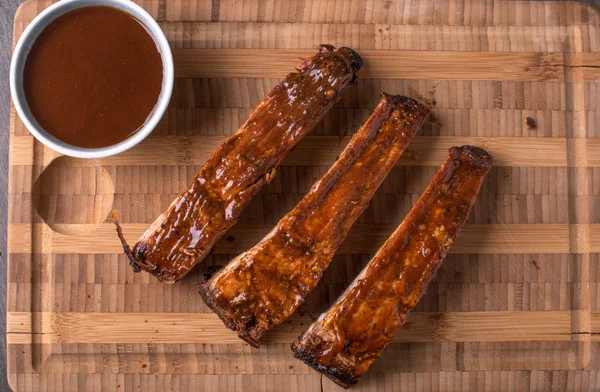 Costeletas em uma tábua de corte com molho de churrasco — Fotografia de Stock