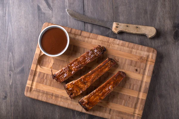 Costeletas em uma tábua de corte com molho de churrasco — Fotografia de Stock