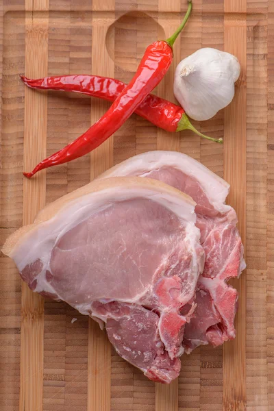 Rohe Schweinekoteletts auf dem Schneidebrett mit etwas Chili und Knoblauch — Stockfoto