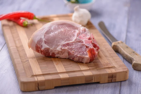 Rohe Schweinekoteletts auf dem Schneidebrett mit etwas Chili und Knoblauch — Stockfoto