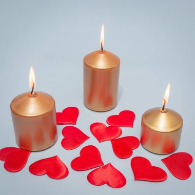 Three burning candles with scarlet hearts