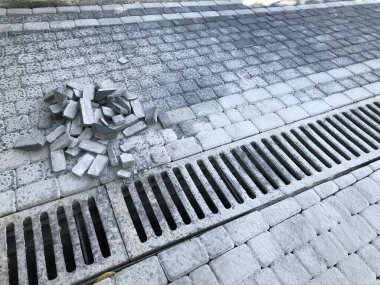 Gündüz vakti şık bahçede kanalizasyon ızgarası olan çeşitli renklerde birbirine kenetlenmiş kaldırımlar