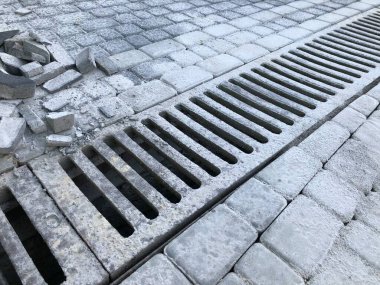 Gündüz vakti şık bahçede kanalizasyon ızgarası olan çeşitli renklerde birbirine kenetlenmiş kaldırımlar