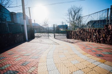Iron gates and fence near the road from paving slabs