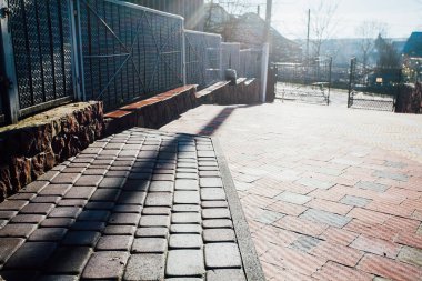 Demir kapılar ve yol kenarındaki çitler kaldırım levhalarından.