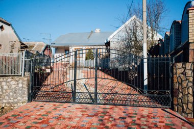 Demir kapılar ve yol kenarındaki çitler kaldırım levhalarından.