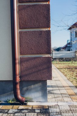 Kenardan gelen suyla yağmur oluğu aşağı akıyor. Taş kiremitlerin etrafında