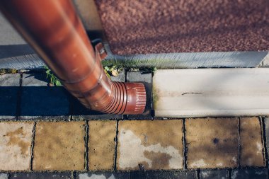 Kenardan gelen suyla yağmur oluğu aşağı akıyor. Taş kiremitlerin etrafında