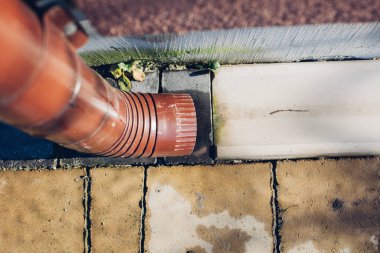 Kenardan gelen suyla yağmur oluğu aşağı akıyor. Taş kiremitlerin etrafında