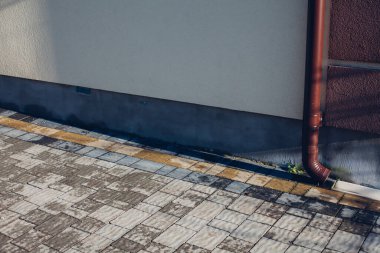 Kenardan gelen suyla yağmur oluğu aşağı akıyor. Taş kiremitlerin etrafında