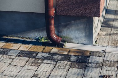 Kenardan gelen suyla yağmur oluğu aşağı akıyor. Taş kiremitlerin etrafında