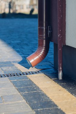 Kenardan gelen suyla yağmur oluğu aşağı akıyor. Taş kiremitlerin etrafında