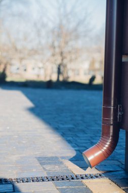 Kenardan gelen suyla yağmur oluğu aşağı akıyor. Taş kiremitlerin etrafında