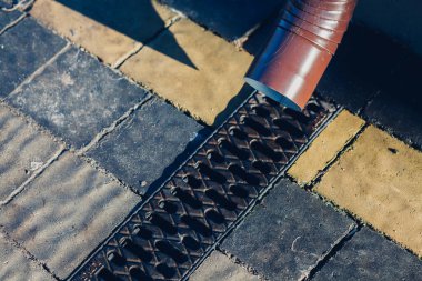 Kenardan gelen suyla yağmur oluğu aşağı akıyor. Taş kiremitlerin etrafında