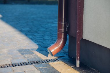 Kenardan gelen suyla yağmur oluğu aşağı akıyor. Taş kiremitlerin etrafında