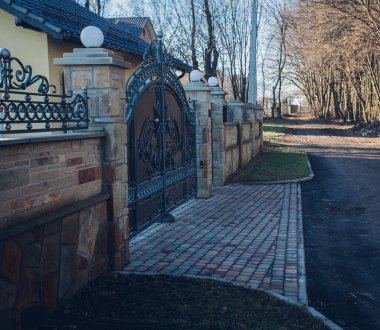 Demir kapılar ve yol kenarındaki çitler kaldırım levhalarından.