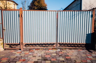 Demir kapılar ve yol kenarındaki çitler kaldırım levhalarından.