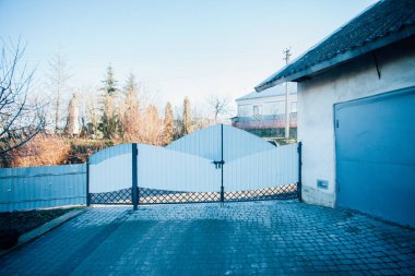 Demir kapılar ve yol kenarındaki çitler kaldırım levhalarından.