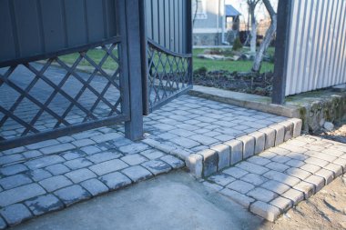 Demir kapılar ve yol kenarındaki çitler kaldırım levhalarından.