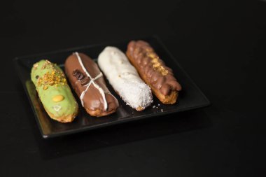 Siyah arka planda tatlı ve renkli ekler. Fransız ekleriName