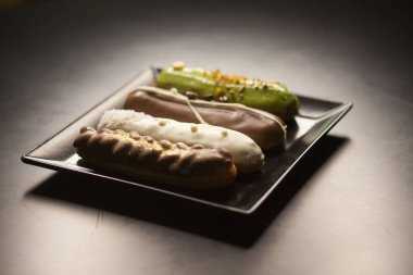 Sweet and colorful eclairs on black background. French eclairs