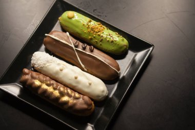 Siyah arka planda tatlı ve renkli ekler. Fransız ekleriName