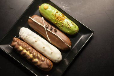 Siyah arka planda tatlı ve renkli ekler. Fransız ekleriName