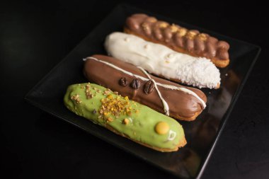 Siyah arka planda tatlı ve renkli ekler. Fransız ekleriName