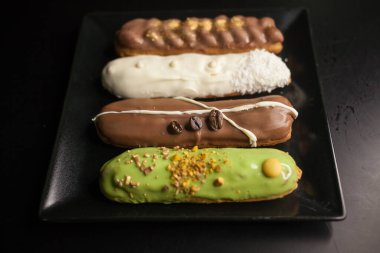 Siyah arka planda tatlı ve renkli ekler. Fransız ekleriName